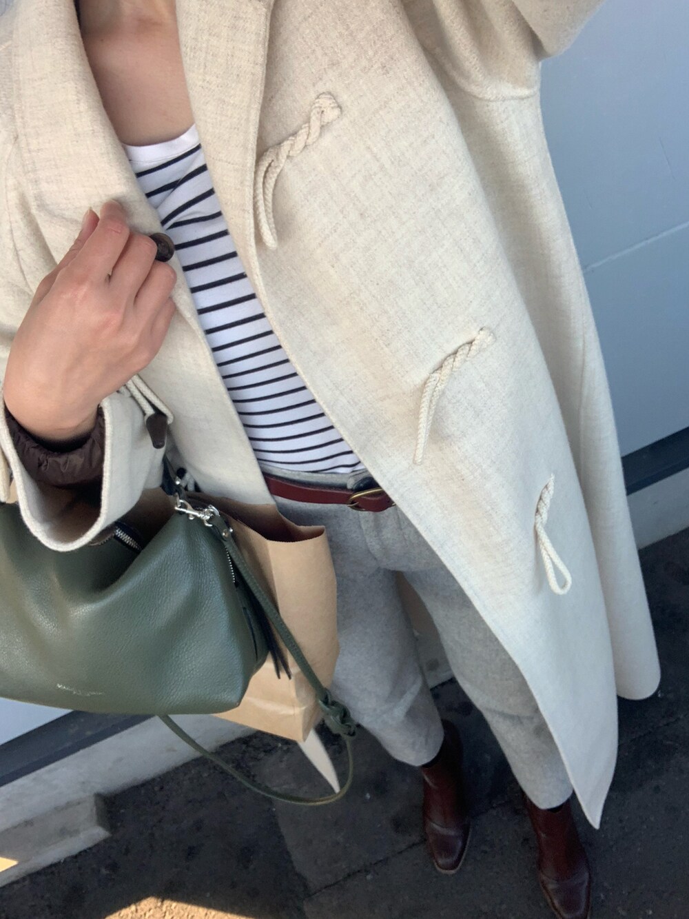 ベージュ系のダッフルコート、グレー系のその他パンツ、ホワイト系のTシャツ/カットソーを着用したレディースの冬コーディネートの2枚目の写真