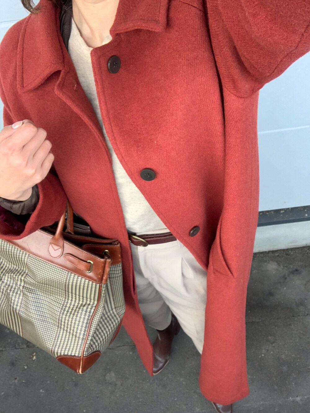 ブラウン系のバッグ、レッド系のステンカラーコート、ベージュ系のその他パンツを着用したレディースの冬コーディネートの2枚目の写真