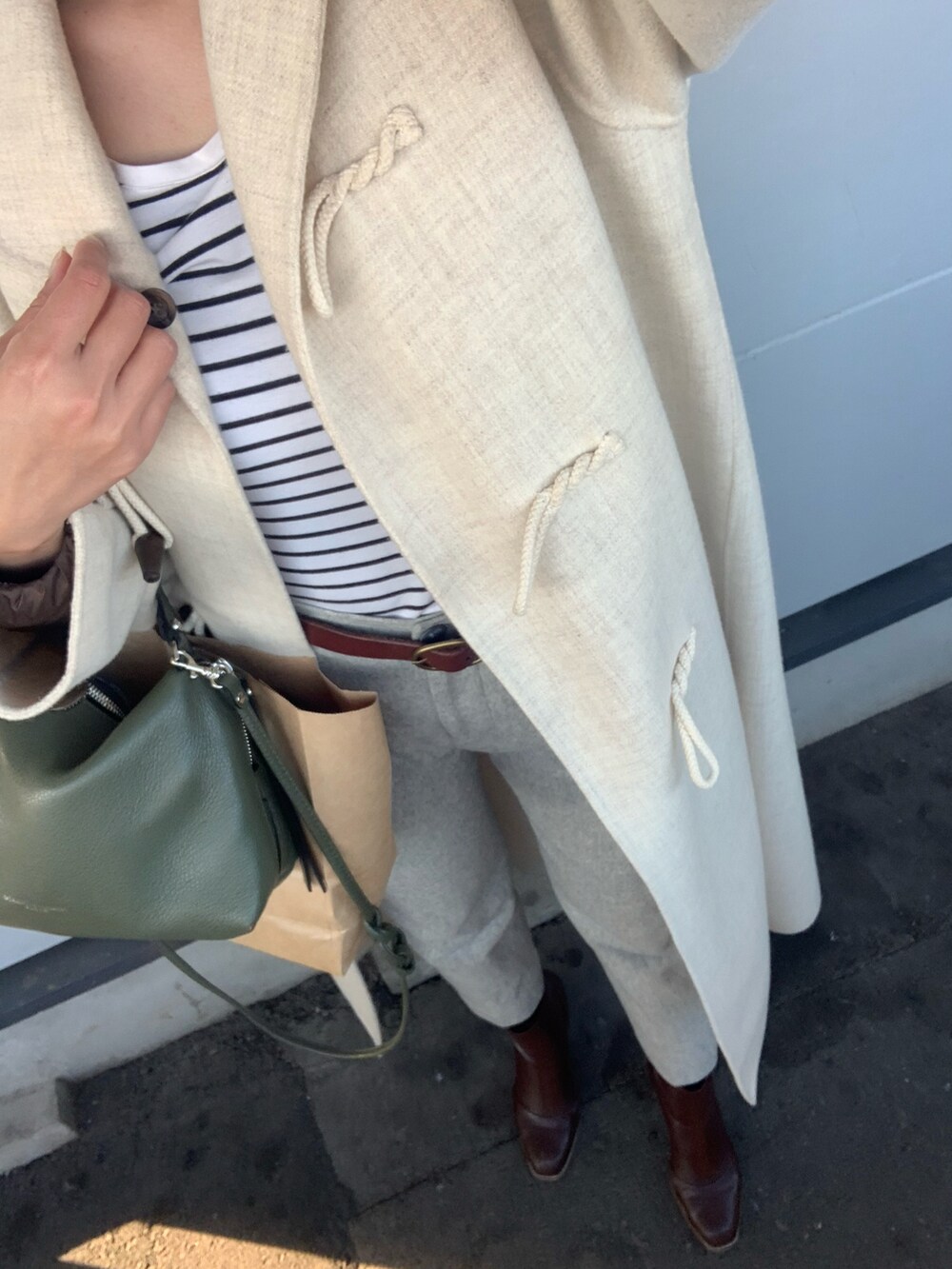 ベージュ系のダッフルコート、グレー系のその他パンツ、ホワイト系のTシャツ/カットソーを着用したレディースの冬コーディネートの3枚目の写真