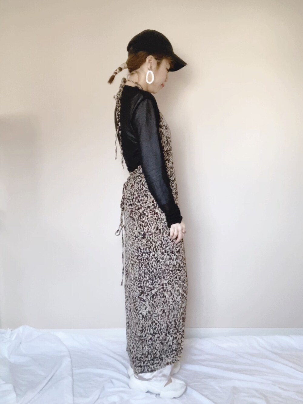 ベージュ系のワンピース、ブラック系のTシャツ/カットソー、ホワイト系のサンダルを着用したレディースの春コーディネートの2枚目の写真