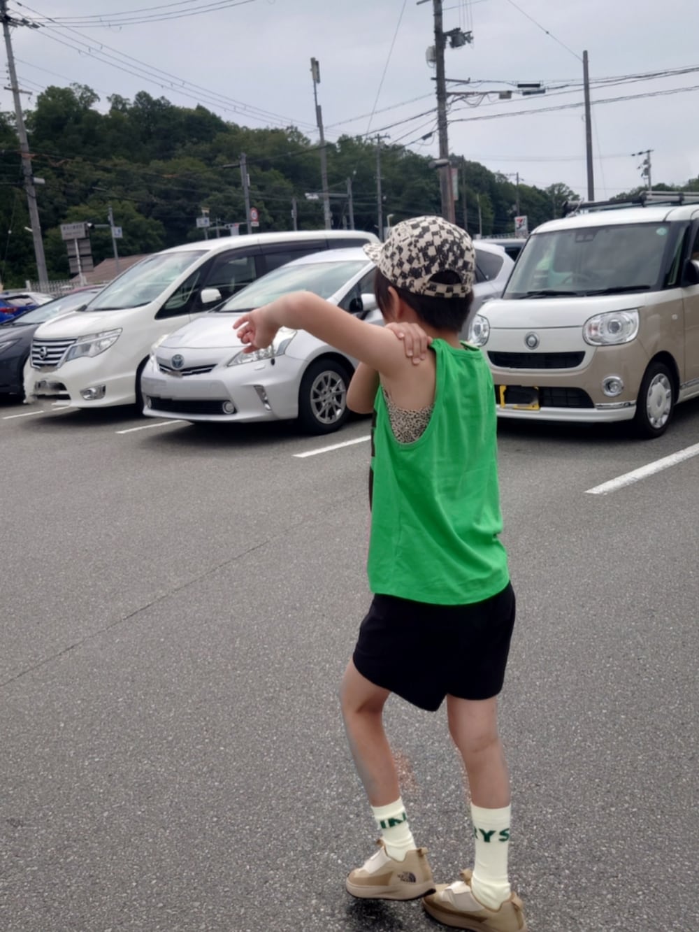 ブラック系のパンツ、ベージュ系のスリッポン、グリーン系のタンクトップを着用したキッズの夏コーディネートの2枚目の写真