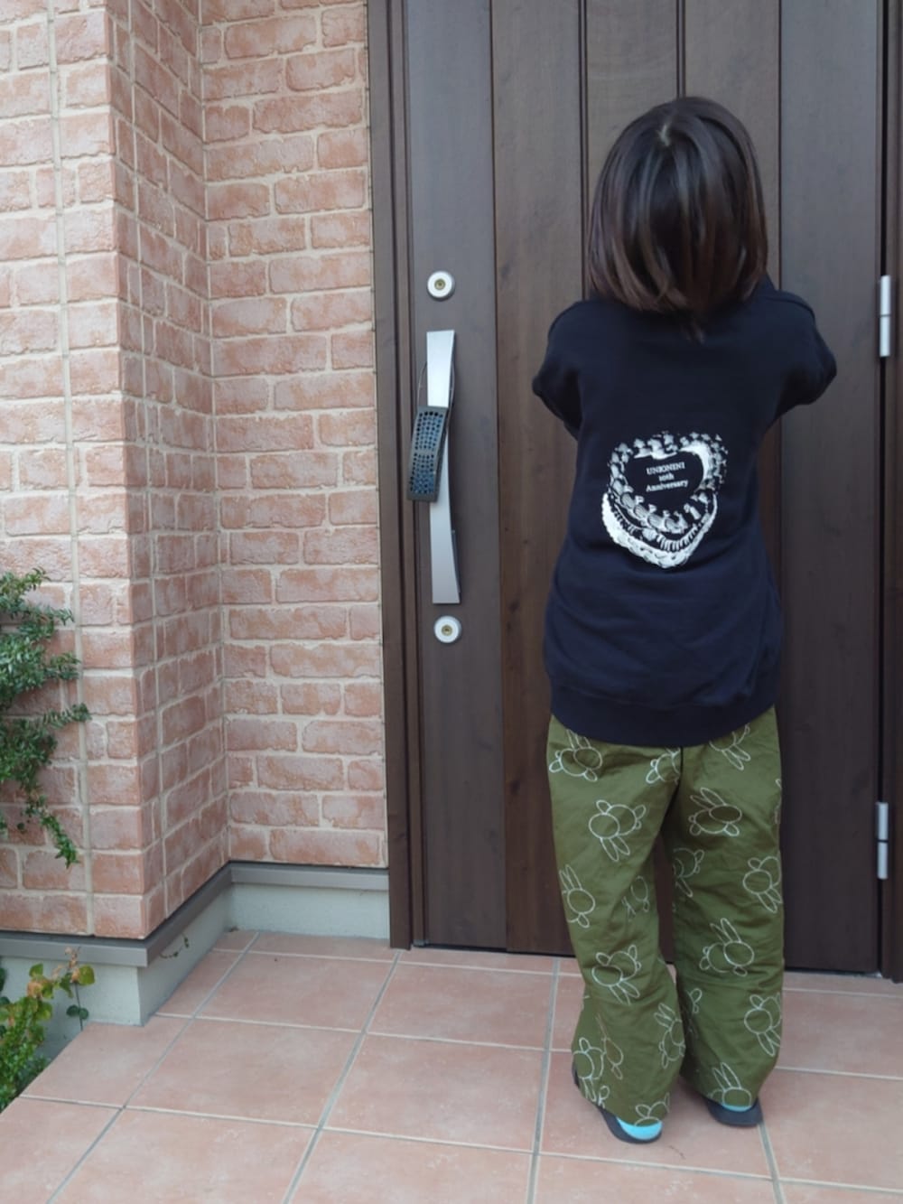 グリーン系のパンツ、ブラック系のサンダル、ブラック系のスウェットを着用したキッズの春コーディネートの2枚目の写真