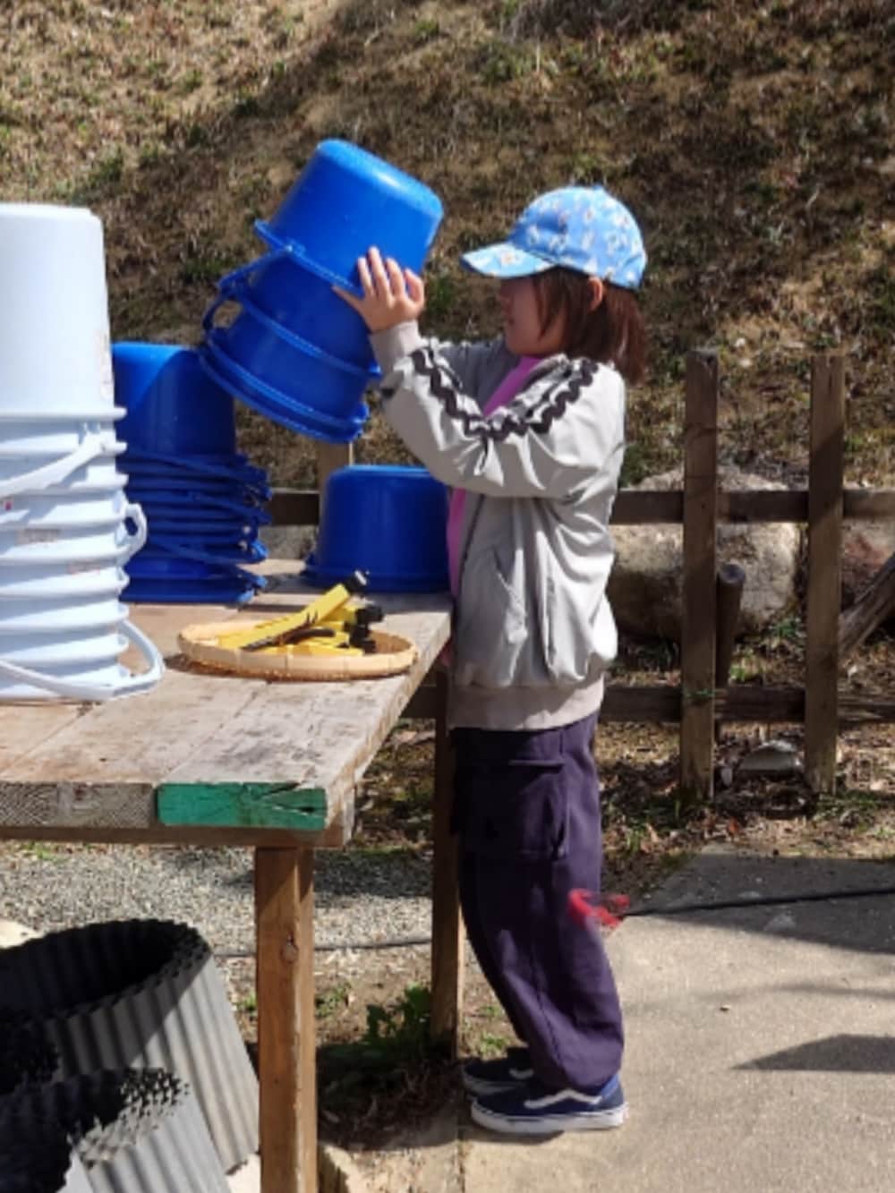 ブラック系のカーゴパンツ、グレー系のナイロンジャケット、ブルー系のスニーカーを着用したキッズの春コーディネートの2枚目の写真