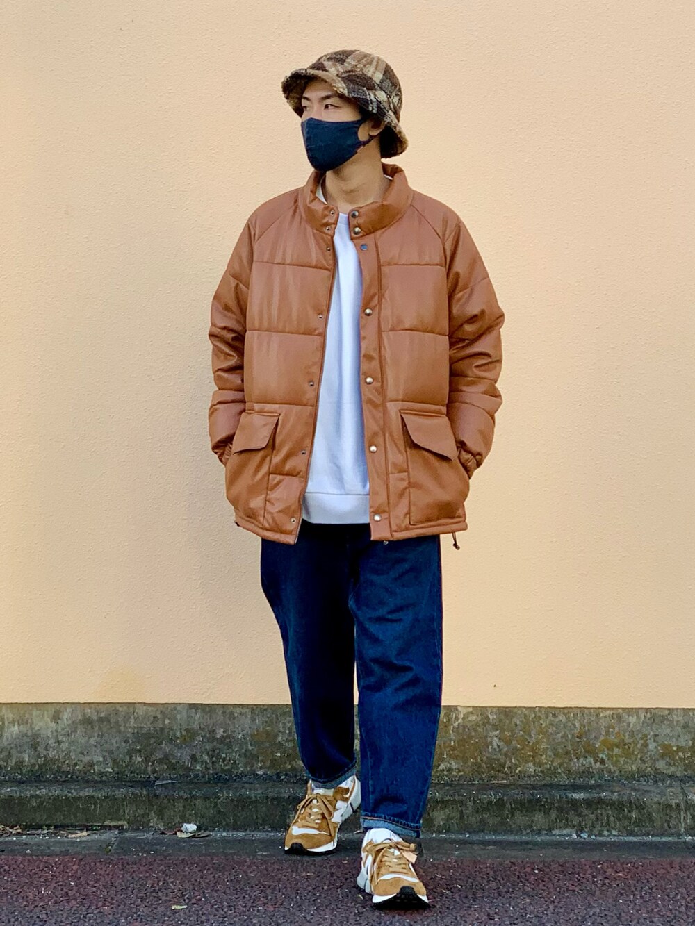 イエロー系のダウンジャケット/コート、ホワイト系のスウェット、ブルー系のデニムパンツを着用したメンズの秋コーディネートの2枚目の写真