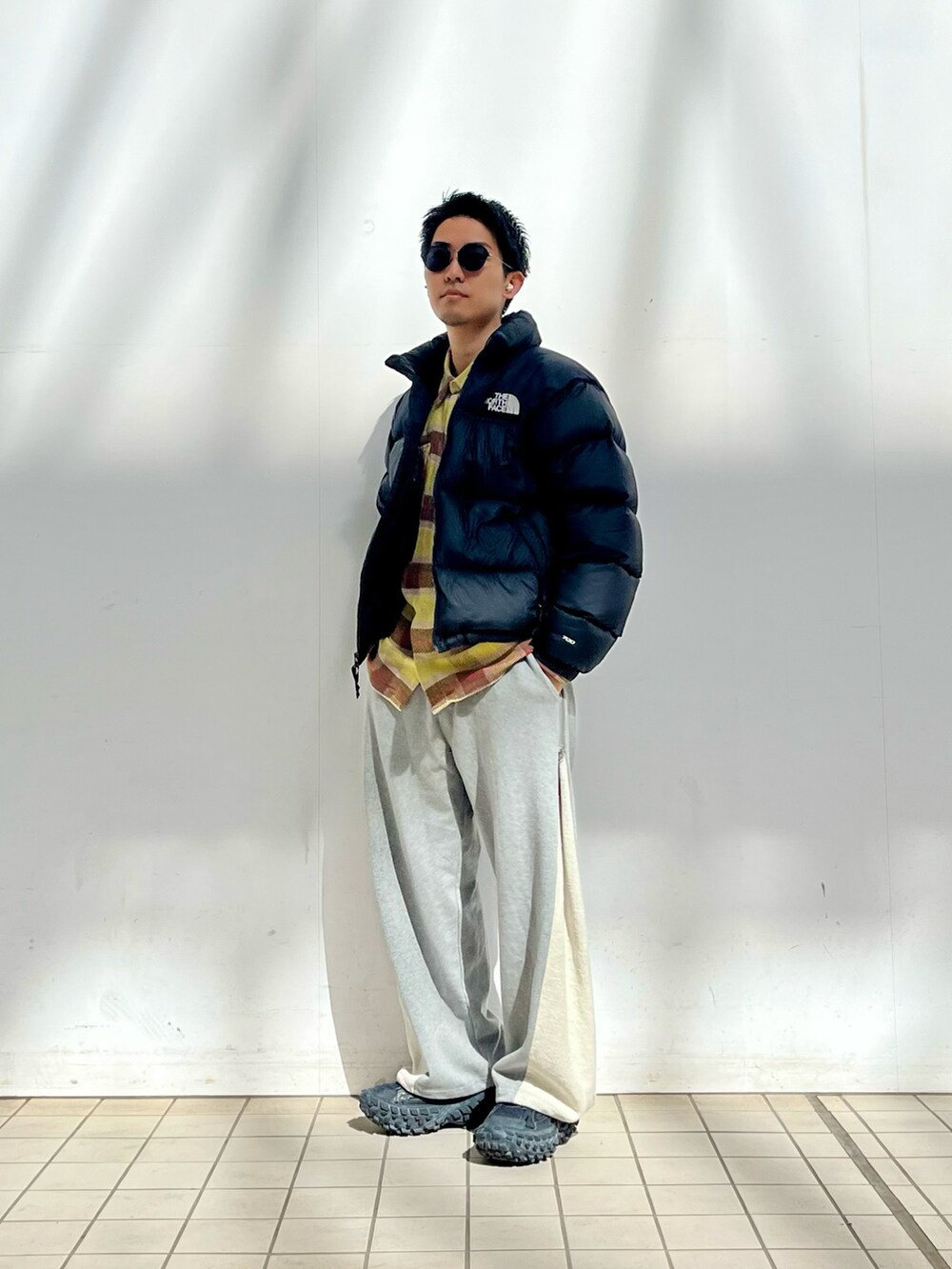 ブラック系のダウンジャケット/コート、イエロー系のシャツ/ブラウス、グレー系のスウェットパンツを着用したメンズの冬コーディネートの2枚目の写真