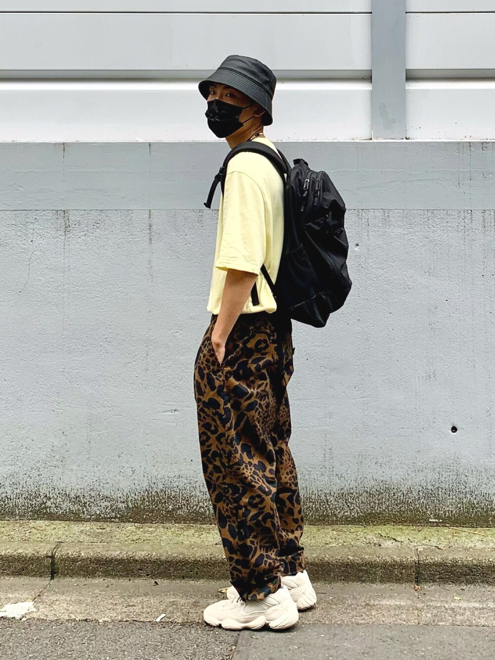 イエロー系のTシャツ/カットソー、ブラウン系のパンツ、ベージュ系のスニーカーを着用したメンズの夏コーディネートの2枚目の写真