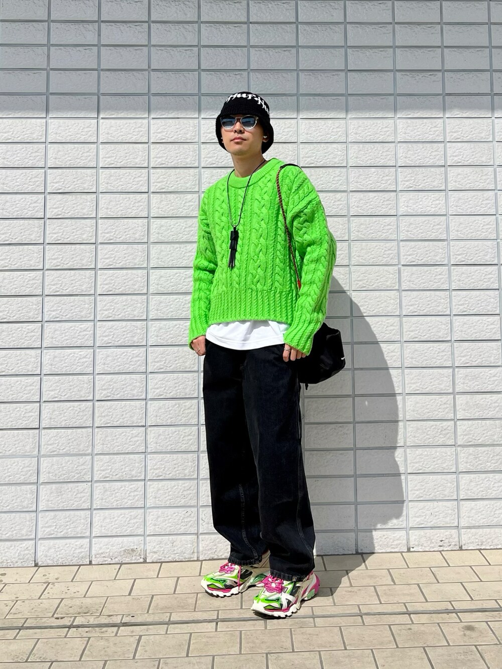 グリーン系のニット/セーター、ブラック系のデニムパンツ、ピンク系のスニーカーを着用したメンズの春コーディネートの2枚目の写真