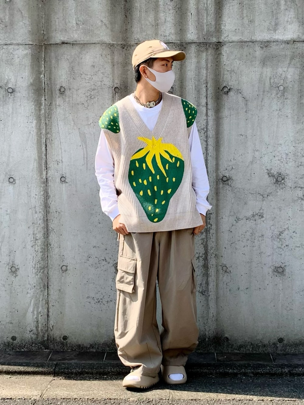 ベージュ系のベスト、ベージュ系のカーゴパンツ、ベージュ系のサンダルを着用したメンズの春コーディネートの2枚目の写真