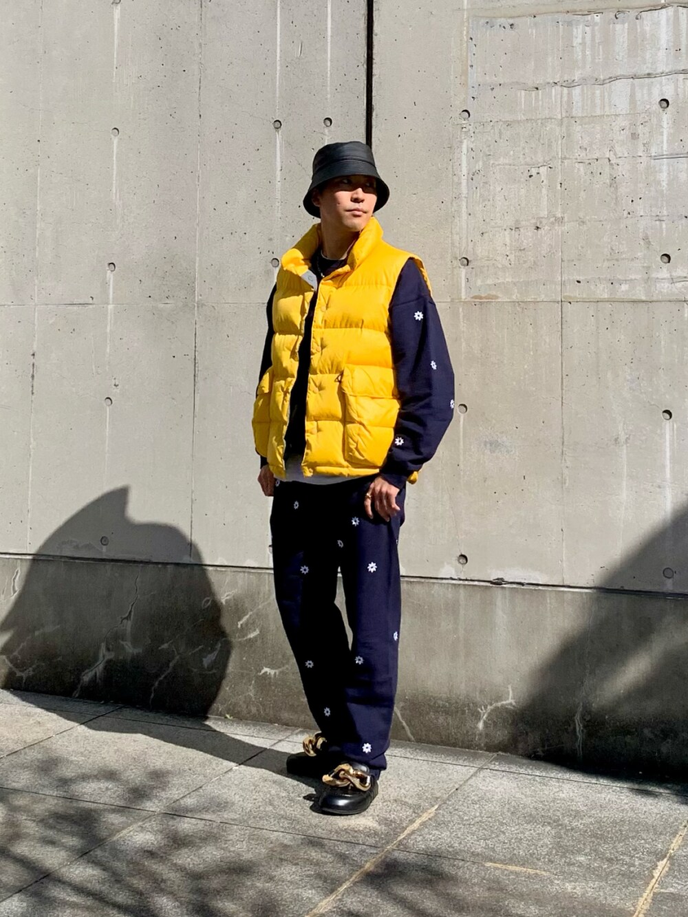イエロー系のダウンベスト、ブルー系のスウェット、ブルー系のスウェットパンツを着用したメンズの冬コーディネートの2枚目の写真