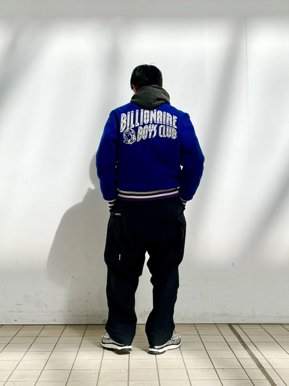 ブルー系のスタジャン、ブラック系のパーカー、ブラック系のカーゴパンツを着用したメンズの春コーディネートの3枚目の写真