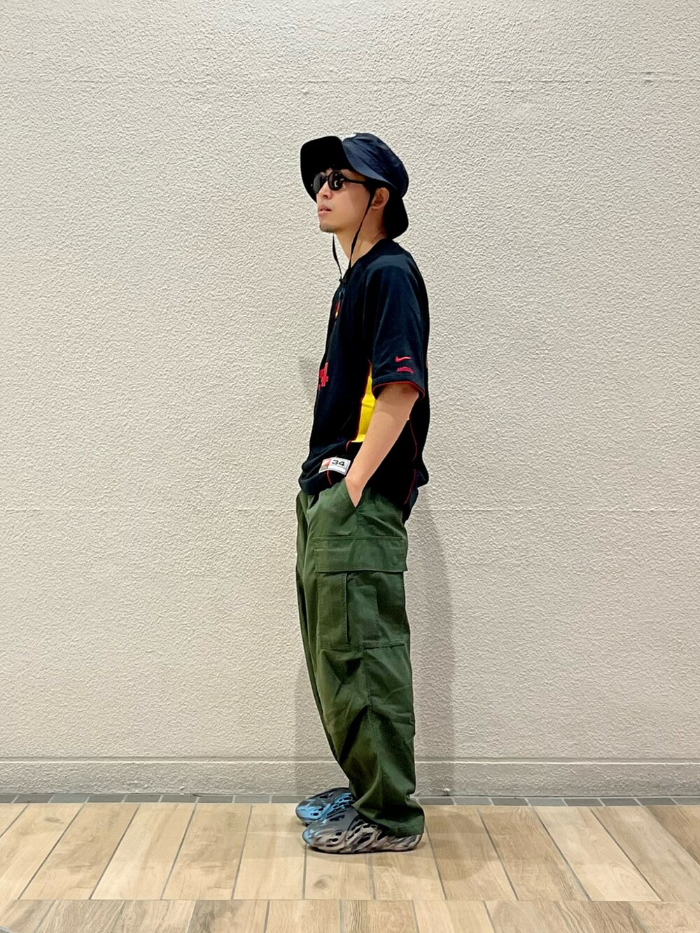 ブラック系のTシャツ/カットソー、グリーン系のカーゴパンツ、ブラウン系のサンダルを着用したメンズの秋コーディネートの2枚目の写真