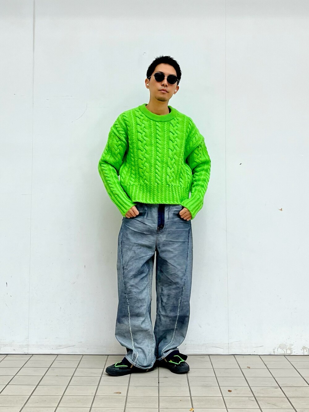 グリーン系のニット/セーター、ブルー系のデニムパンツ、ブラック系のスニーカーを着用したメンズの秋コーディネートの2枚目の写真