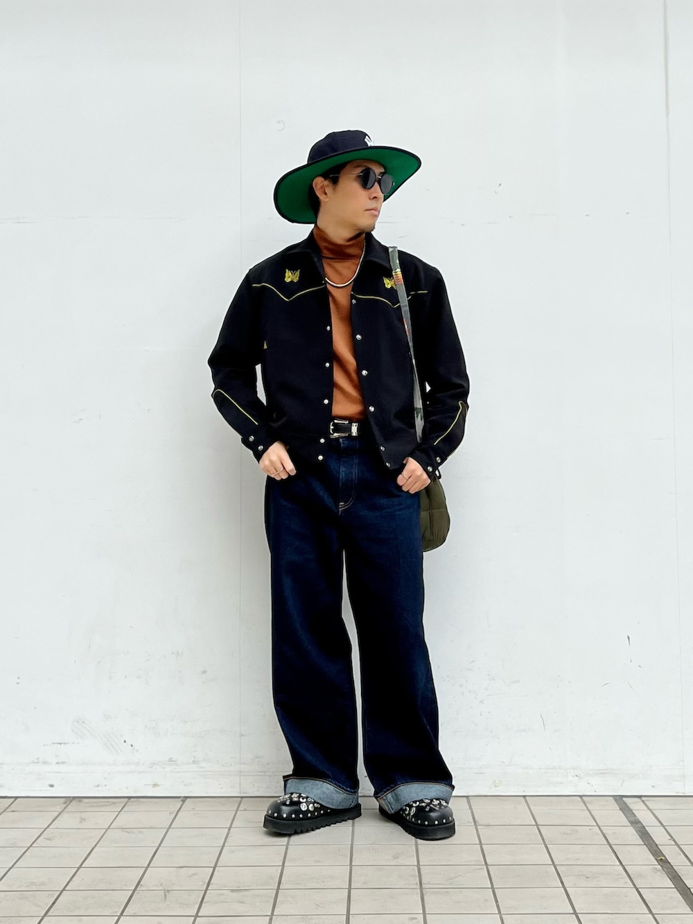 ブラック系のその他アウター、ブルー系のデニムパンツ、グリーン系のショルダーバッグを着用したメンズの冬コーディネートの2枚目の写真