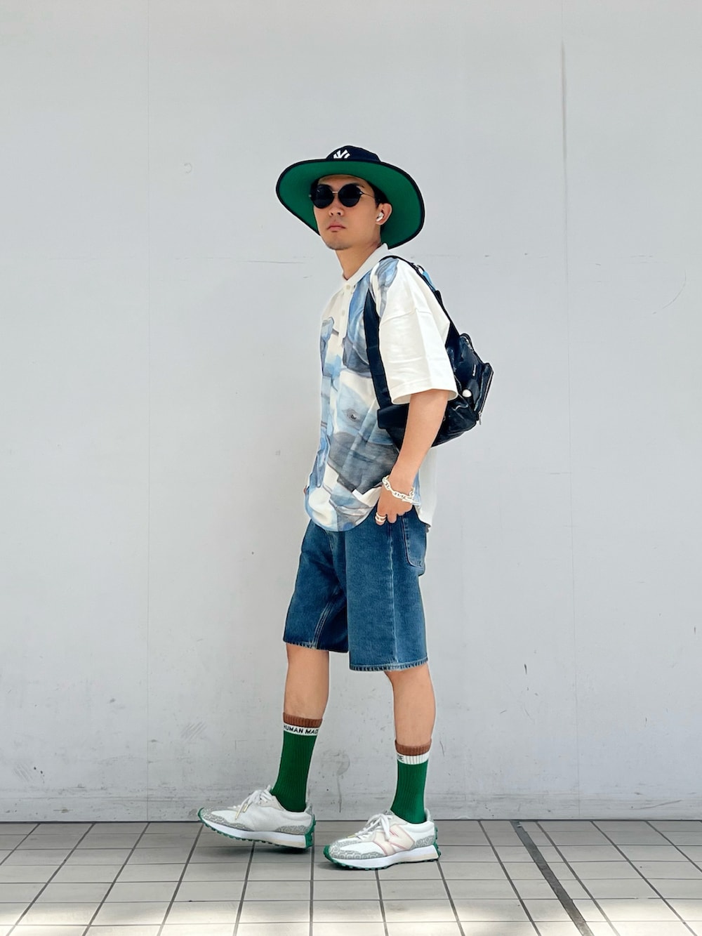 ホワイト系のポロシャツ、ブルー系のデニムパンツ、ホワイト系のスニーカーを着用したメンズの夏コーディネートの2枚目の写真