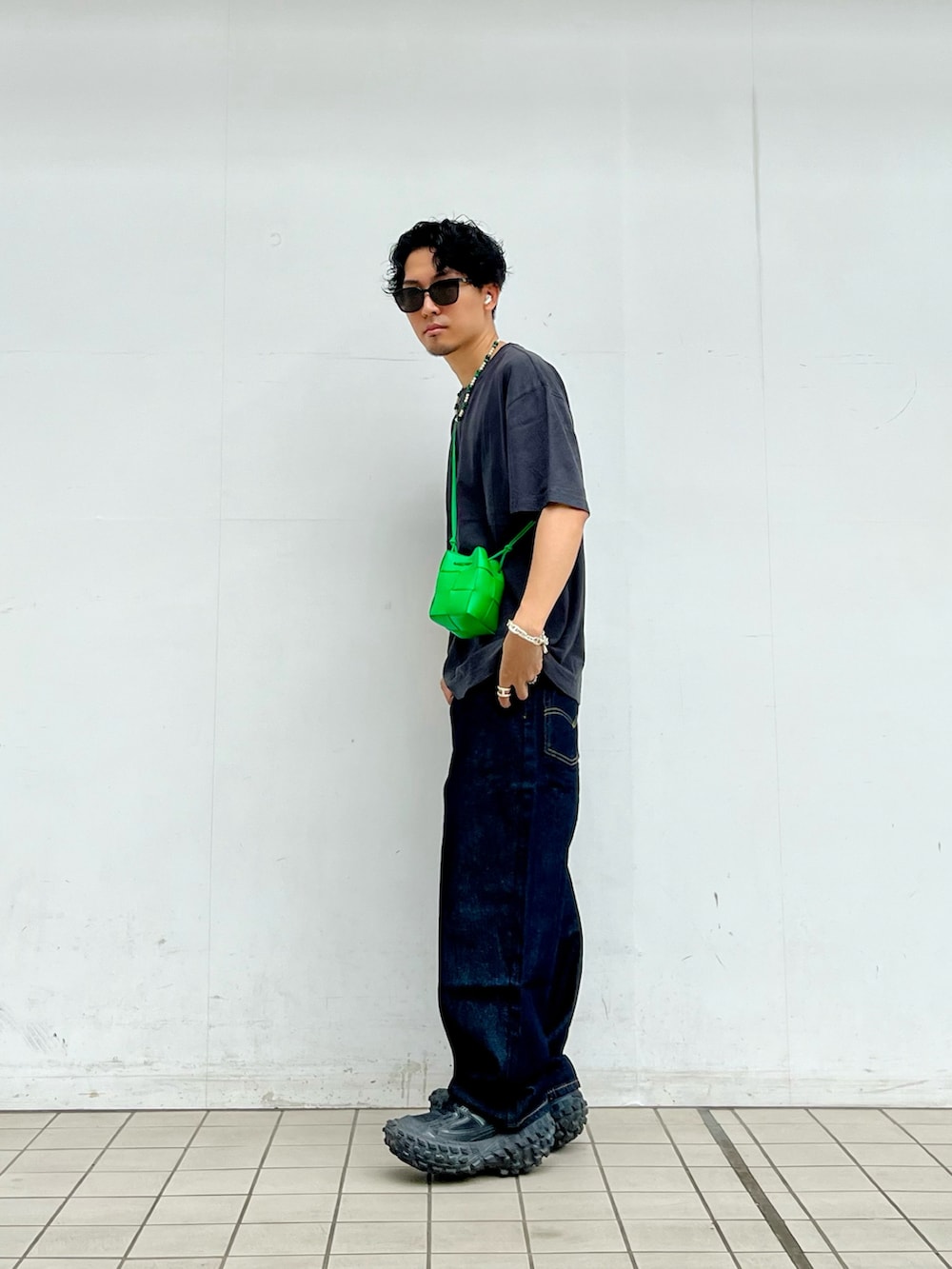 グレー系のTシャツ/カットソー、ブルー系のデニムパンツ、ブラック系のスニーカーを着用したメンズの夏コーディネートの2枚目の写真
