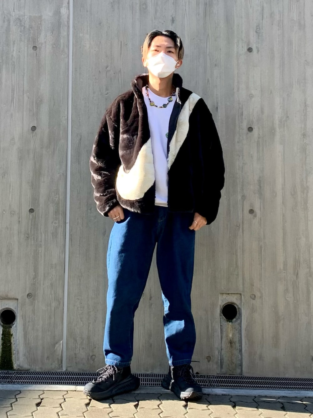 ブラック系のブルゾン、ホワイト系のスウェット、ブルー系のデニムパンツを着用したメンズの秋コーディネートの2枚目の写真