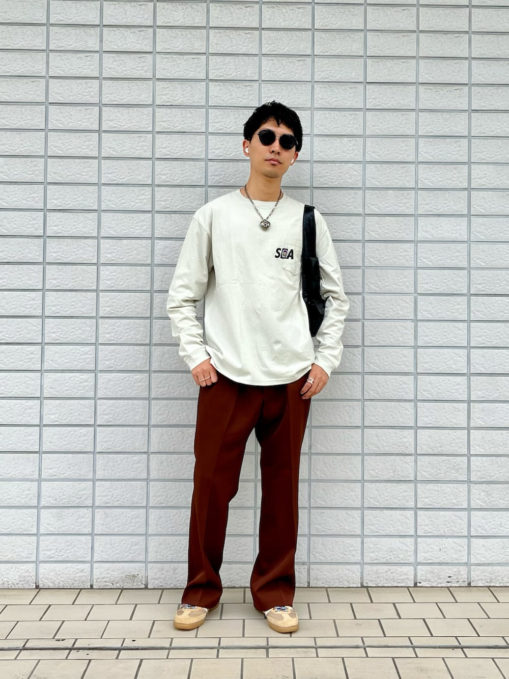 ベージュ系のTシャツ/カットソー、ブラウン系のスラックス、ベージュ系のスニーカーを着用したメンズの春コーディネートの2枚目の写真