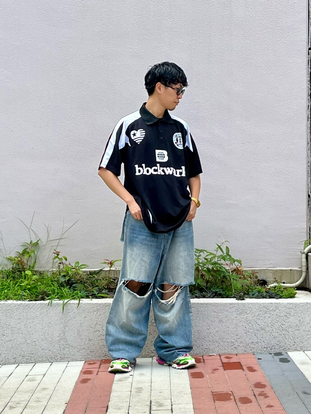 ブラック系のポロシャツ、ブルー系のデニムパンツ、ピンク系のスニーカーを着用したメンズの夏コーディネートの2枚目の写真