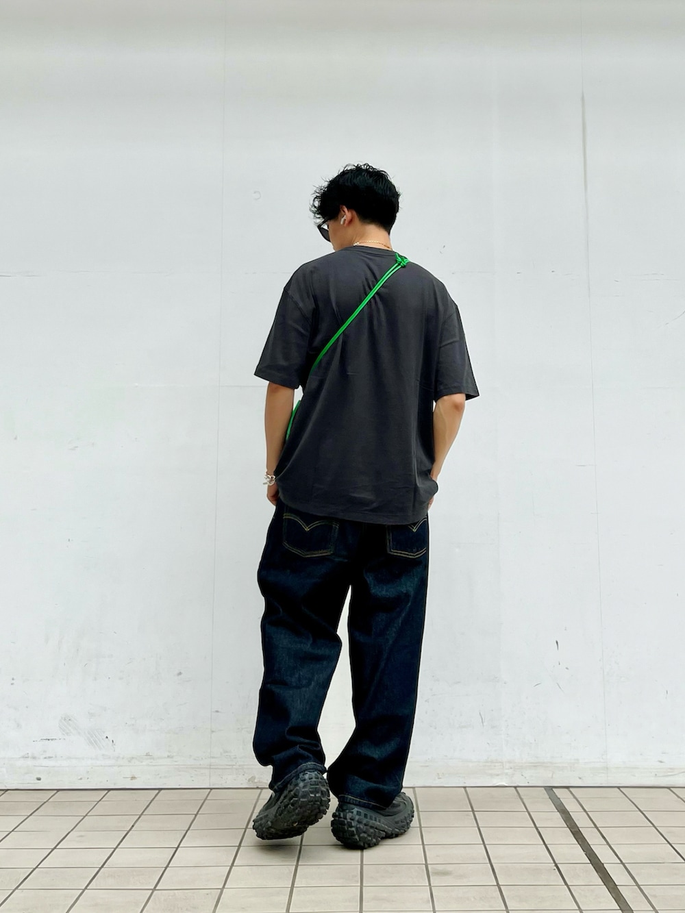 グレー系のTシャツ/カットソー、ブルー系のデニムパンツ、ブラック系のスニーカーを着用したメンズの夏コーディネートの3枚目の写真