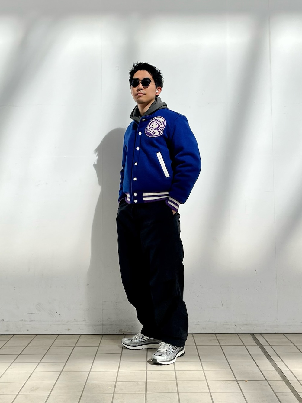 ブルー系のスタジャン、ブラック系のパーカー、ブラック系のカーゴパンツを着用したメンズの春コーディネートの2枚目の写真