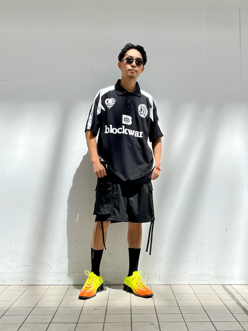 ブラック系のポロシャツ、ブラック系のカーゴパンツ、イエロー系のスニーカーを着用したメンズの秋コーディネートの2枚目の写真