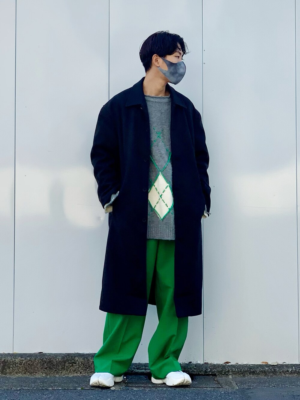ブラック系のステンカラーコート、グリーン系のスラックス、ホワイト系のサンダルを着用したメンズの冬コーディネートの2枚目の写真