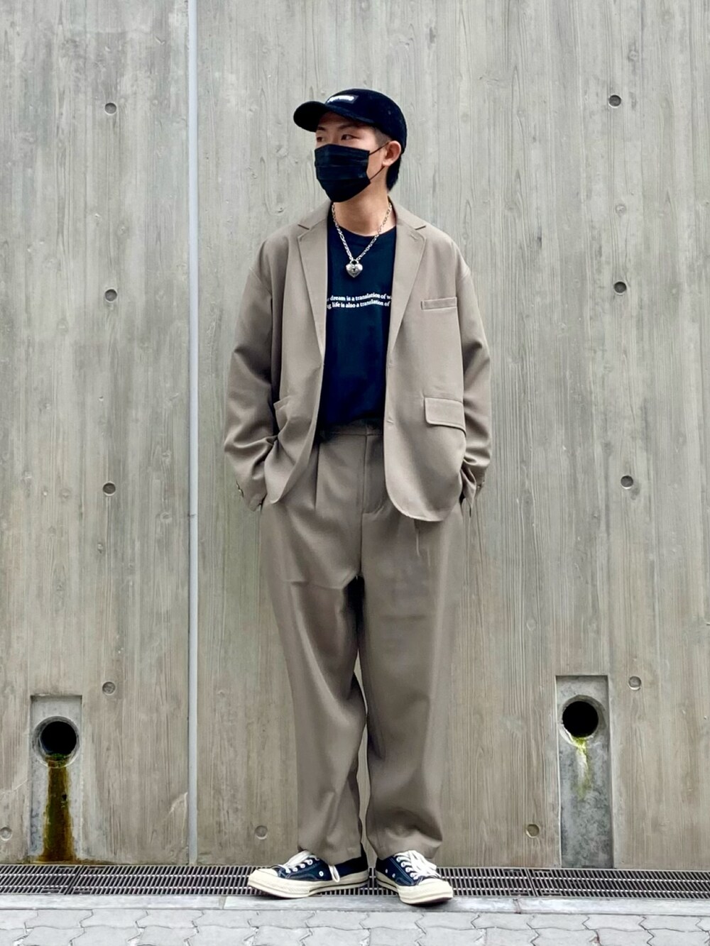 ベージュ系のテーラードジャケット、ブラック系のTシャツ/カットソー、ブラック系のスニーカーを着用したメンズの春コーディネートの2枚目の写真