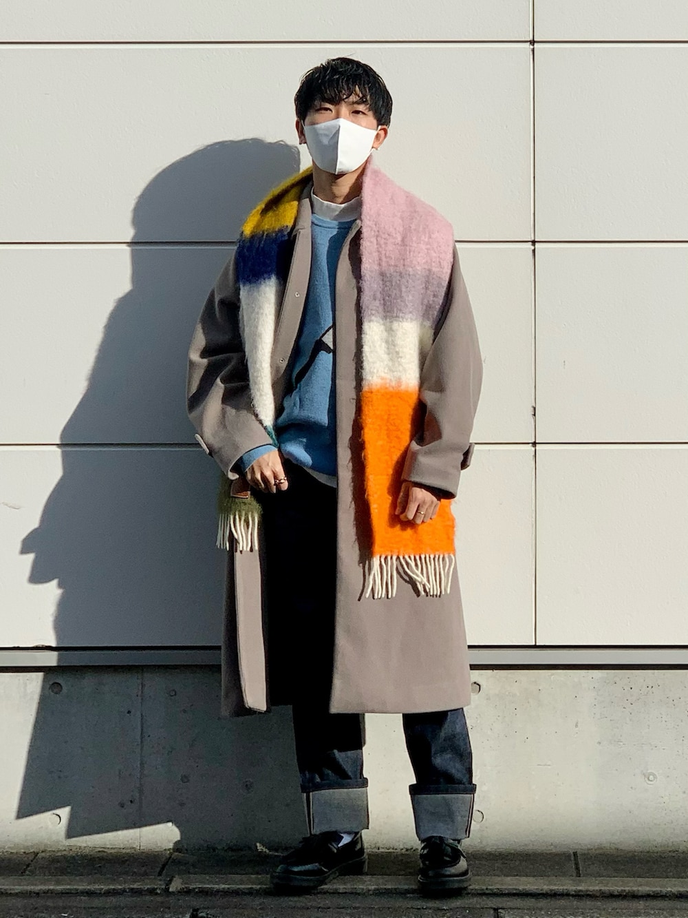 ベージュ系のステンカラーコート、ブルー系のニット/セーター、ブルー系のデニムパンツを着用したメンズの冬コーディネートの2枚目の写真