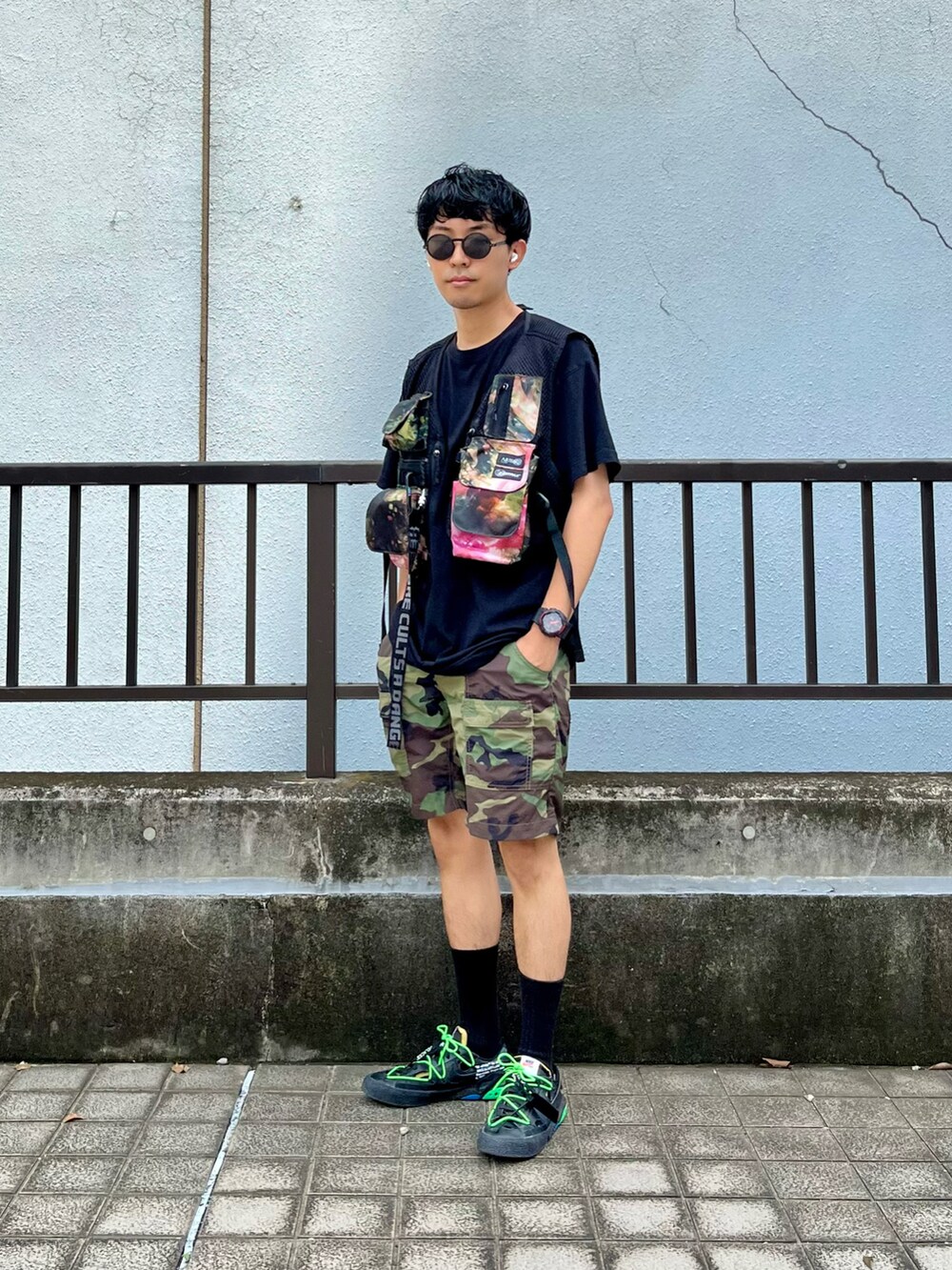 ブラック系のベスト、グリーン系のパンツ、ブラック系のスニーカーを着用したメンズの夏コーディネートの2枚目の写真