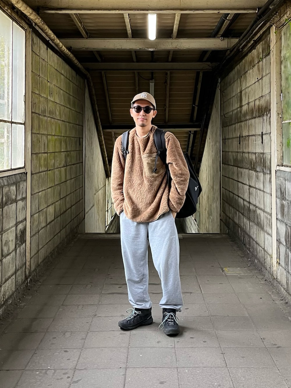 ベージュ系のTシャツ/カットソー、ブラック系のスニーカー、ベージュ系のキャップを着用したメンズの秋コーディネートの2枚目の写真