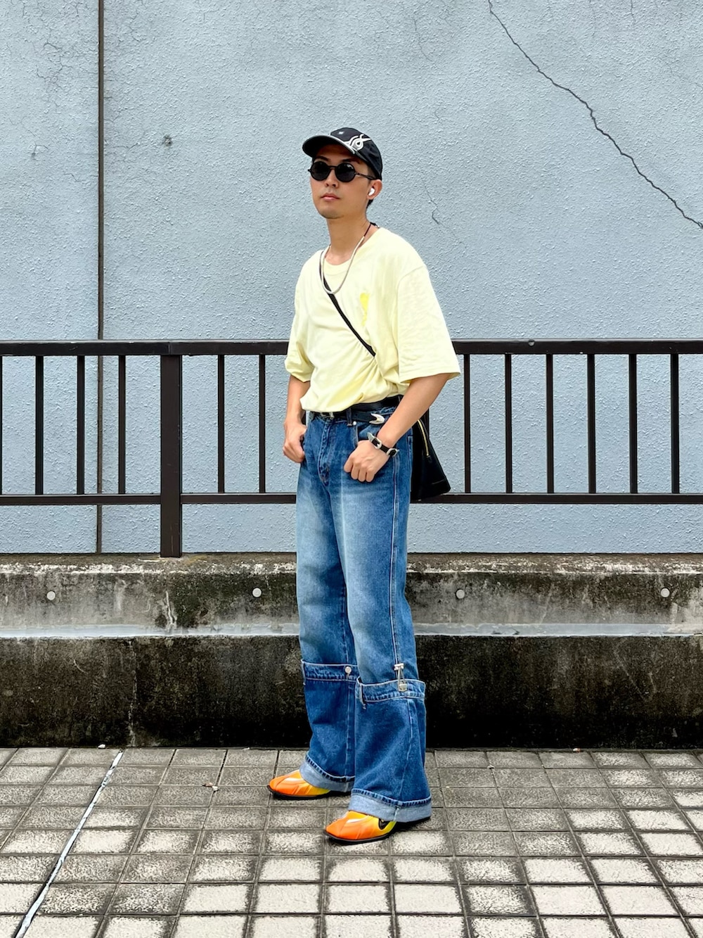イエロー系のTシャツ/カットソー、ブルー系のデニムパンツ、イエロー系のスニーカーを着用したメンズの夏コーディネートの2枚目の写真
