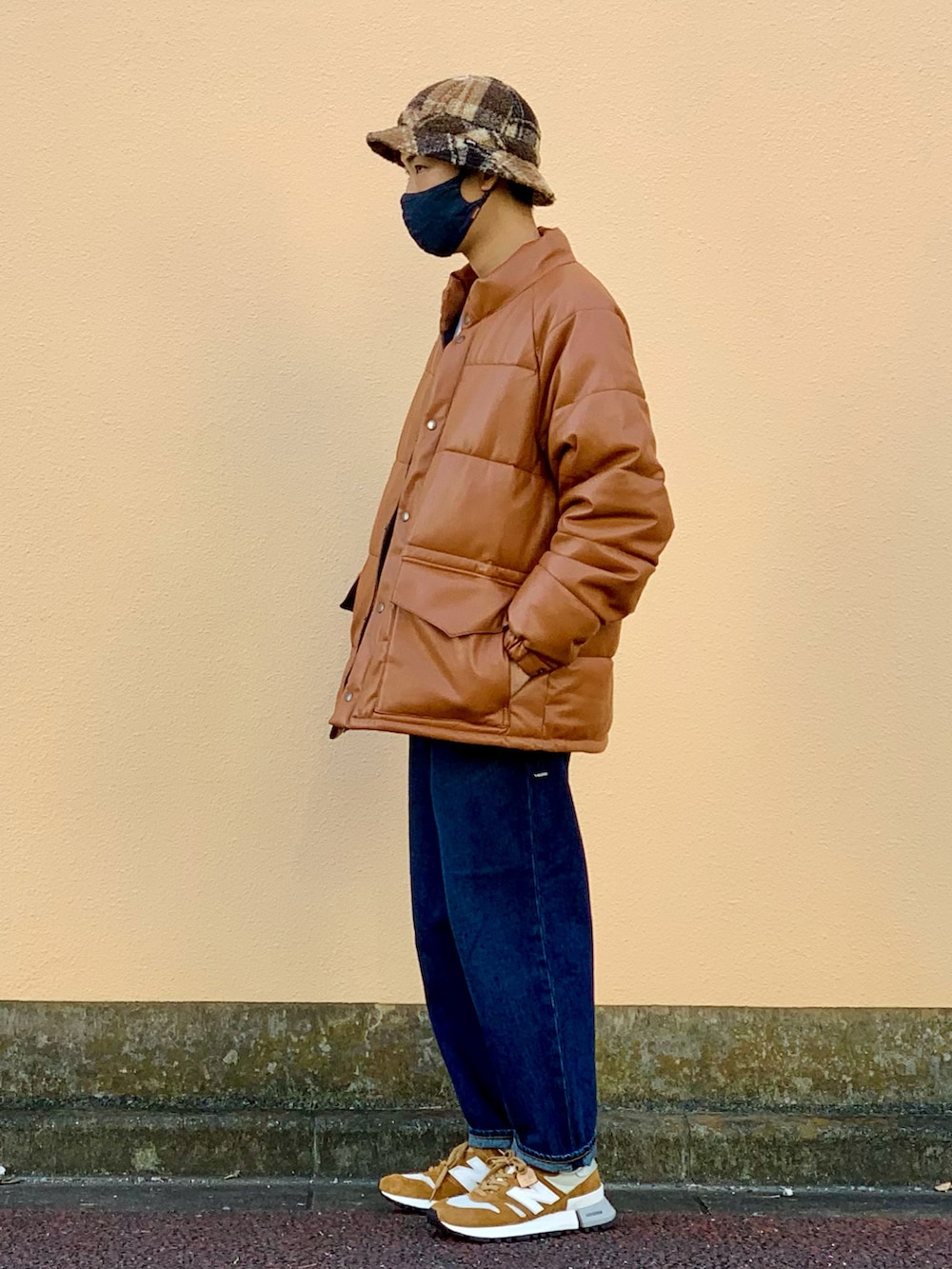 イエロー系のダウンジャケット/コート、ホワイト系のスウェット、ブルー系のデニムパンツを着用したメンズの秋コーディネートの3枚目の写真