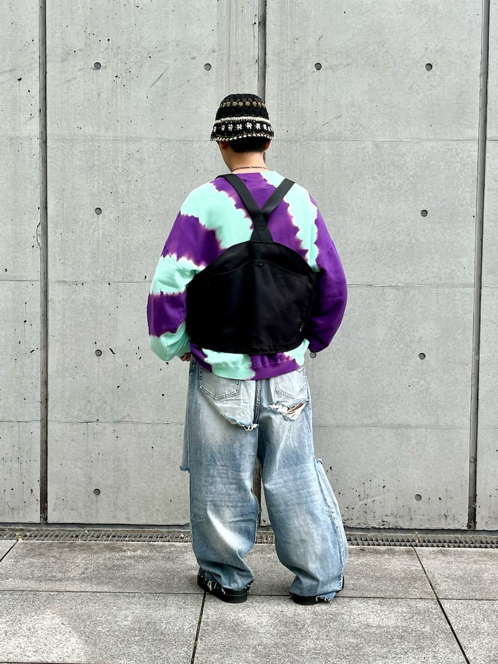 ブラック系のベスト、パープル系のスウェット、ブルー系のデニムパンツを着用したメンズの春コーディネートの2枚目の写真