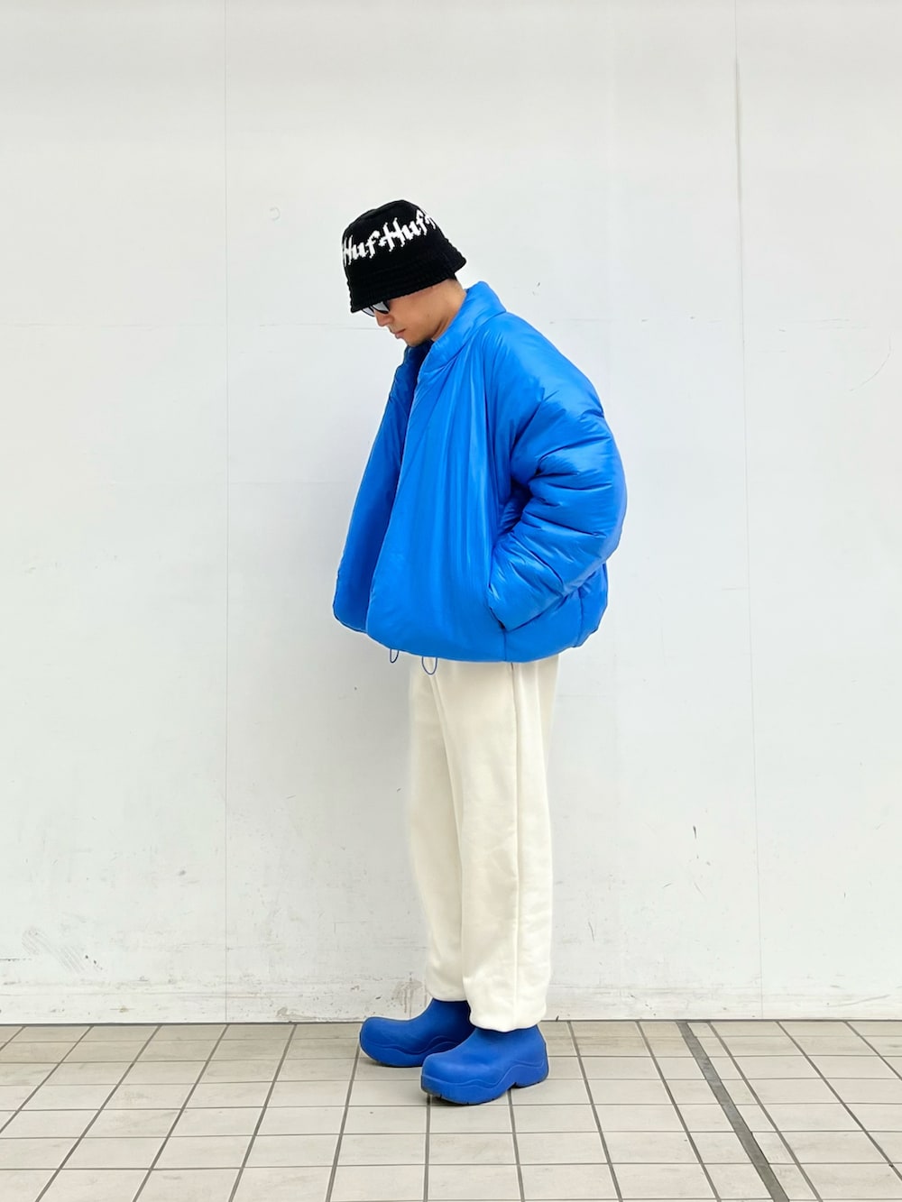 ブルー系のダウンジャケット/コート、グレー系のニット/セーター、ホワイト系のスウェットパンツを着用したメンズの冬コーディネートの2枚目の写真