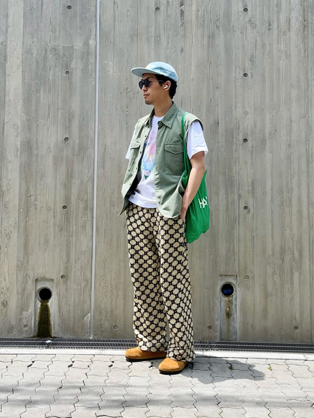 グリーン系のベスト、ホワイト系のTシャツ/カットソー、ベージュ系のスウェットパンツを着用したメンズの夏コーディネートの2枚目の写真