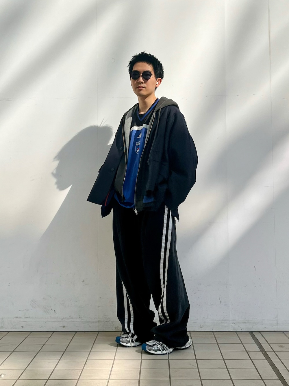 ブルー系のテーラードジャケット、ブラック系のパーカー、ブラック系のスウェットパンツを着用したメンズの春コーディネートの2枚目の写真