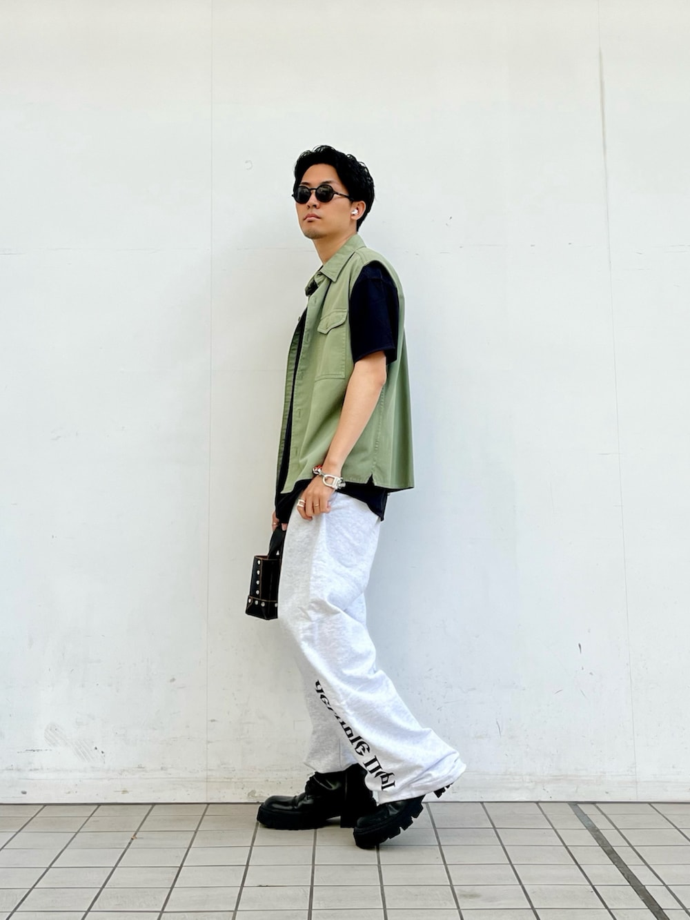 グリーン系のベスト、グレー系のスウェットパンツ、ブラック系のブーツを着用したメンズの夏コーディネートの2枚目の写真