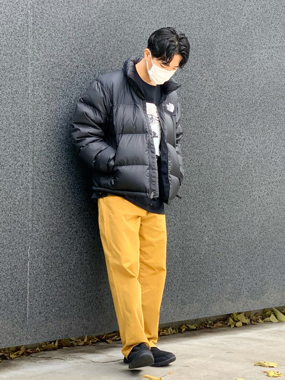 ブラック系のダウンジャケット/コート、ブラック系のTシャツ/カットソー、イエロー系のデニムパンツを着用したメンズの冬コーディネートの2枚目の写真