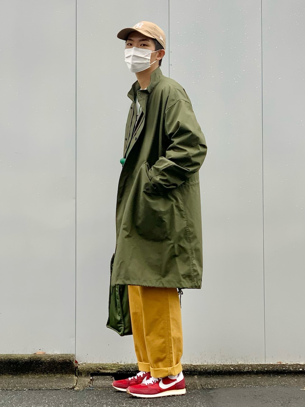 グリーン系のモッズコート、ホワイト系のニット/セーター、イエロー系のデニムパンツを着用したメンズの冬コーディネートの2枚目の写真