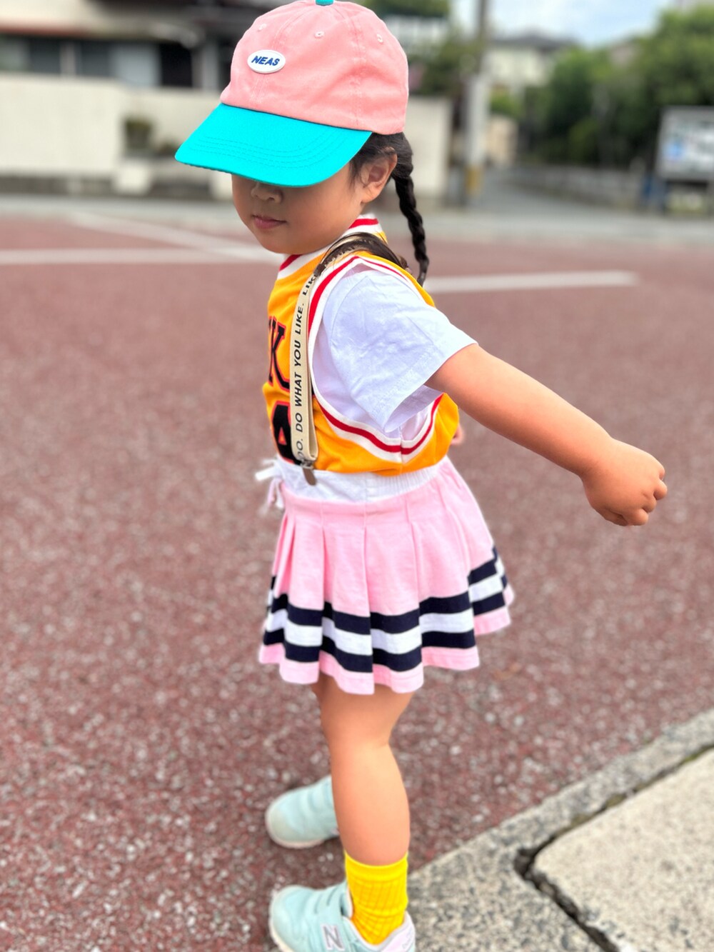 イエロー系のTシャツ/カットソー、ピンク系のスカート、グリーン系のスニーカーを着用したキッズの春コーディネートの2枚目の写真