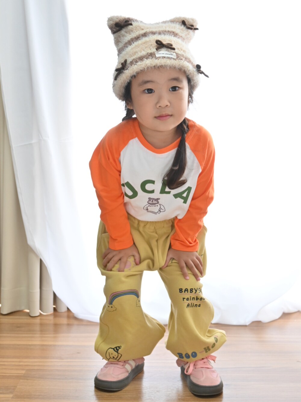 オレンジ系のTシャツ/カットソー、イエロー系のスウェットパンツ、ピンク系のスニーカーを着用したキッズの秋コーディネートの2枚目の写真