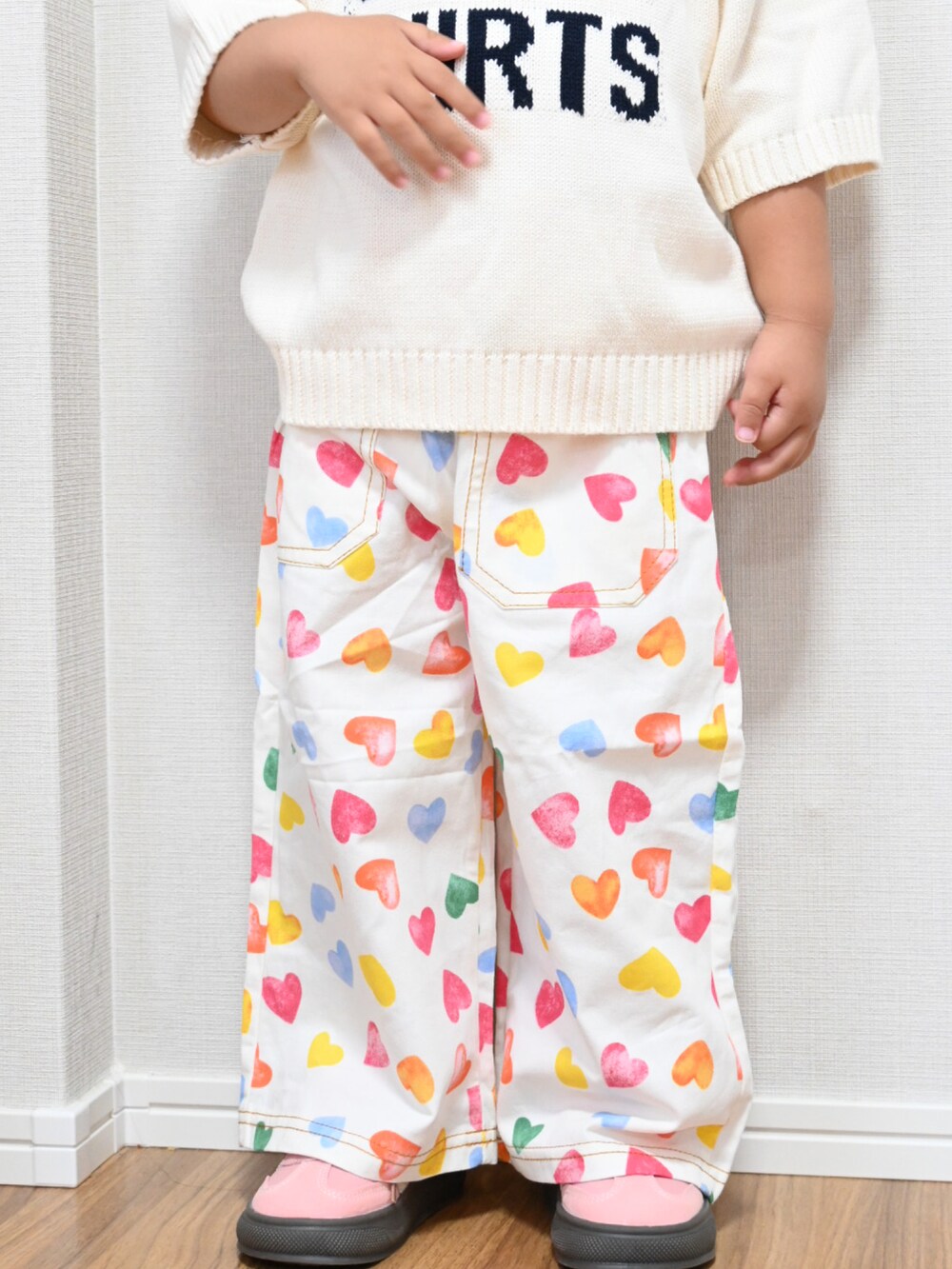 ホワイト系のデニムパンツ、ホワイト系のニット/セーター、ピンク系のスニーカーを着用したキッズの夏コーディネートの2枚目の写真