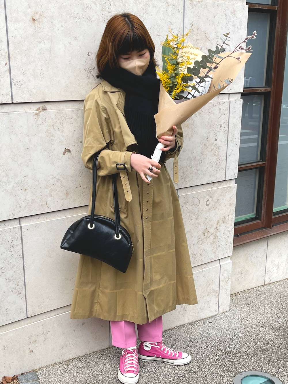 ピンク系のスニーカー、ベージュ系のトレンチコート、ブラック系のハンドバッグを着用したレディースの春コーディネートの2枚目の写真