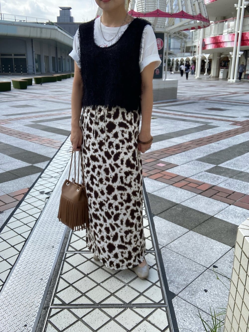 ブラック系のベスト、ホワイト系のTシャツ/カットソー、ベージュ系のスカートを着用したレディースの秋コーディネートの2枚目の写真