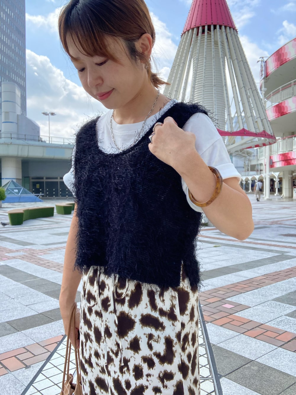 ブラック系のベスト、ホワイト系のTシャツ/カットソー、ベージュ系のスカートを着用したレディースの秋コーディネートの3枚目の写真