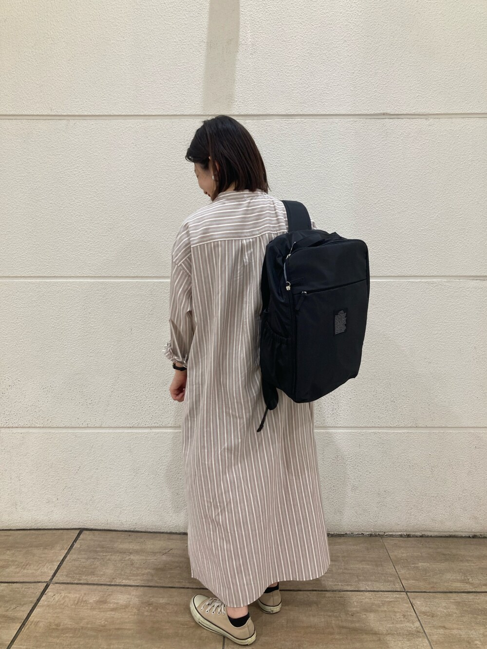 ブラック系のトートバッグ、ベージュ系のシャツワンピース、ベージュ系のスニーカーを着用したレディースの春コーディネートの2枚目の写真