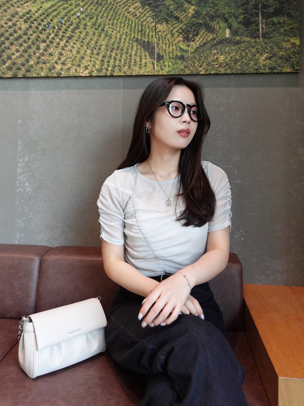 ブラック系のデニムパンツ、シルバー系のTシャツ/カットソー、ベージュ系のショルダーバッグを着用したレディースの夏コーディネートの2枚目の写真