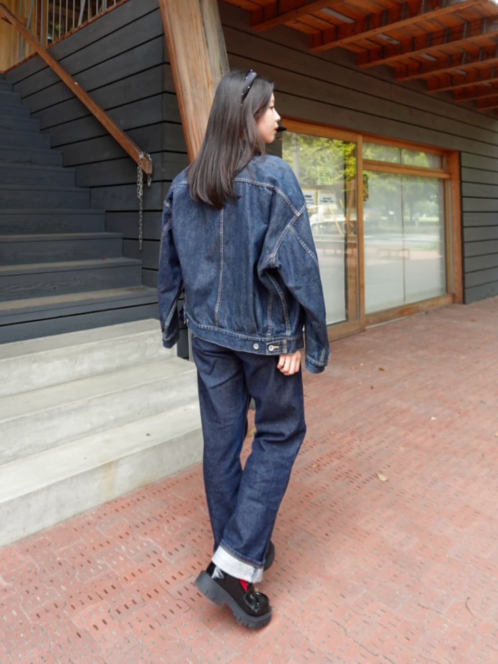 レッド系のニット/セーター、ブルー系のデニムジャケット、ブラウン系のバッグを着用したレディースの秋コーディネートの2枚目の写真