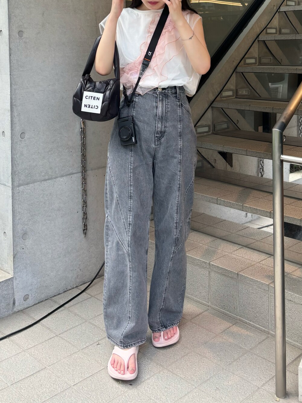 ピンク系のサンダル、ブラック系のデニムパンツ、ブラック系のハンドバッグを着用したレディースの春コーディネートの2枚目の写真