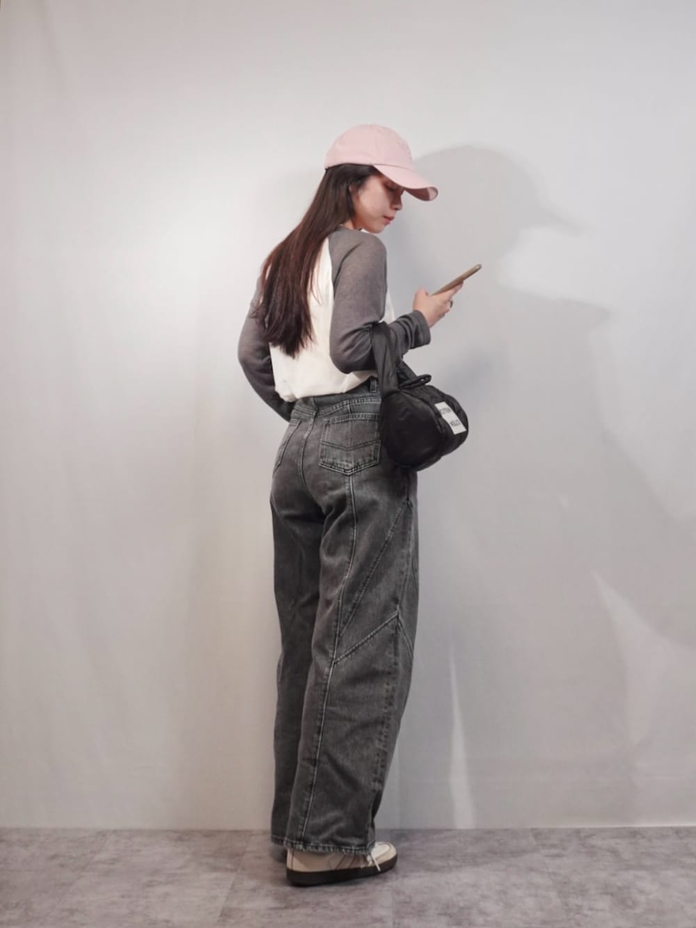 グレー系のデニムパンツ、ホワイト系のスニーカー、ブラック系のハンドバッグを着用したレディースの春コーディネートの2枚目の写真